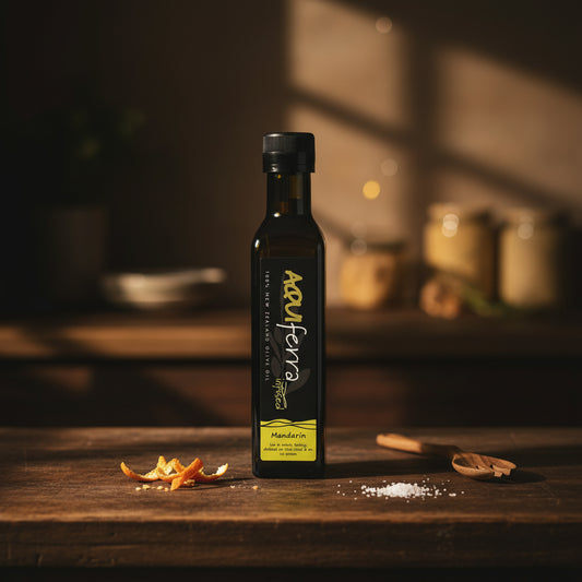 Aquiferra Mandarin olive oil bottle on a dark rustic kitchen bench with subtle mandarin peel and Mediterranean props.